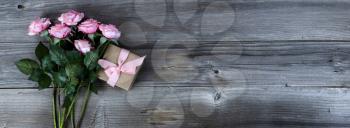 Overhead view of pink roses and giftbox on rustic wood for Mothers Day concept 