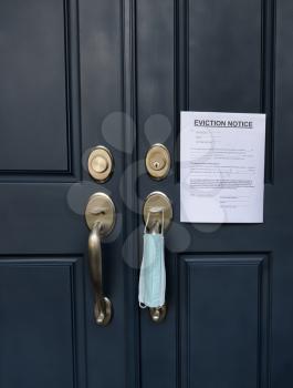Home front door with eviction notice and facemask for renter in default during Covid 19 pandemic 