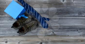 Work shoes with blue necktie and gift box for Fathers Day Concept background on vintage wooden planks 