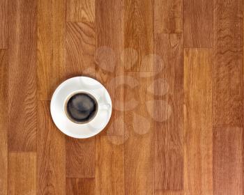 White cup of coffee on wooden table. Above view.
