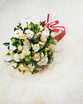 Bouquet for bride of roses, eustomy and pistachios with a wedding gift on beige background.