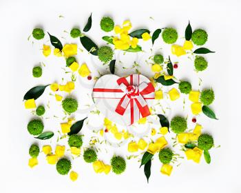 Gift in shape of heart with pattern from petals of rose and chrysanthemum flowers, ficus leaves and ripe rowan on white background. Overhead view. Flat lay.