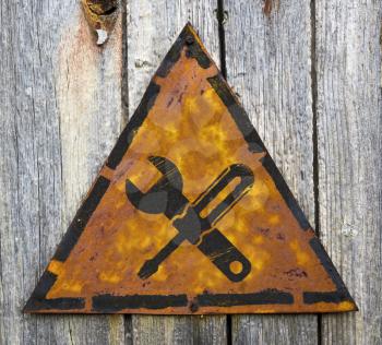 Royalty Free Photo of a Crossed Wrench and Screwdriver on a Rusty Sign Against a Wooden Wall
