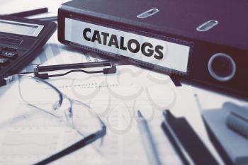 Catalogs - Office Folder on Background of Working Table with Stationery, Glasses, Reports. Business Concept on Blurred Background. Toned Image.