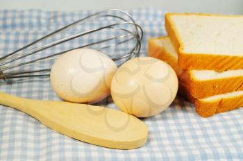 Eggs and bread with batter and wooden spoon ready to prapare french toasts