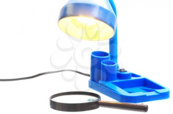 Lit blue plastic lamp shining on a magnifying glass isolated on white