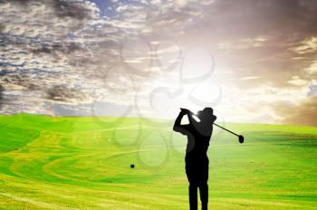 Silhouette of a golfer against the early morning sky and sun