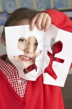 Female Primary School Pupil Cutting Out Paper Shapes In Craft Lesson