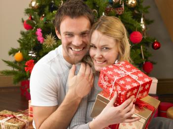 Young couple with gifts in front of Christmas tree