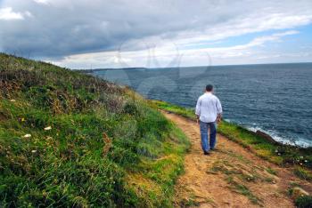 A man walking on a hiking trail along the coast of Brittany, France