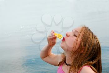 Young girl blowing soap bubbles