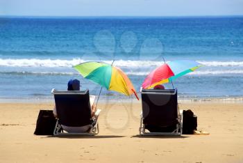 A couple relaxing on a beach under colorful umbrellas