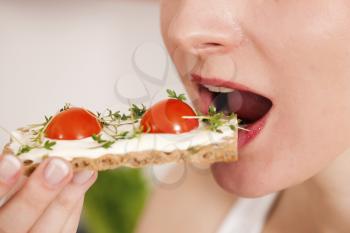 Woman eating healthy in her diet, having a crispbread with cream cheese, cress, and tomatoes