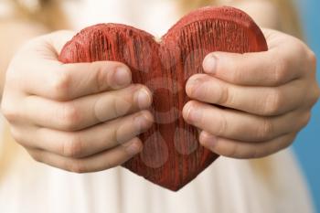 Close-up of red wooden heart in child's hands showing it