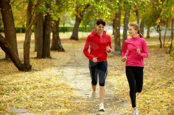 Two girls racing in autumn park 