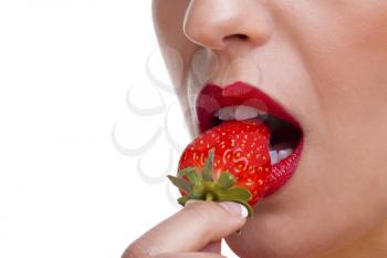 Close up of a woman wearing red lipstick eating a stawberry, white background.