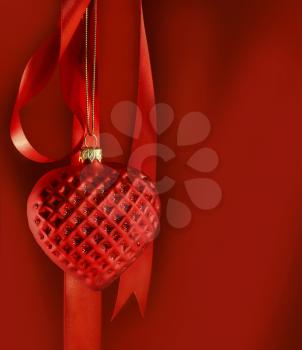Royalty Free Photo of a Red Heart Hanging From a Red Ribbon on a Red Background