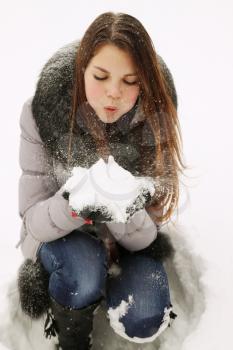 Young girl blowing on snow in their hands