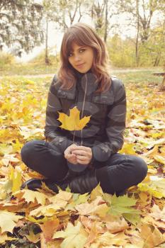 Portrait of a girl sitting on the autumn leaves