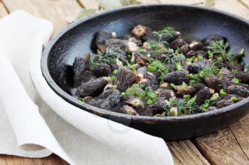 Morels mushrooms fried in a pan with onions