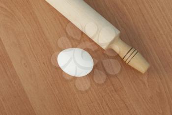 Wooden rolling pin and eggs on the table