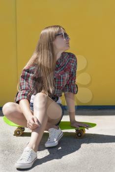 Young girl is resting sitting on a skateboard.