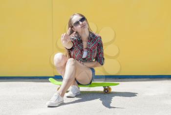 Stylish cheerful young girl with skateboard resting on the street.