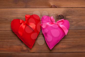 Two hearts with ribbon on wooden background.