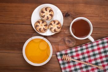 Cup of tea biscuits and honey on wooden background.