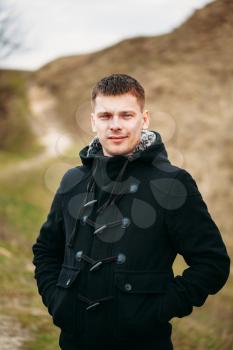Young Handsome Man Stayed In Field, Meadow In Autumn Day. Casual Style - Jeans, Jacket