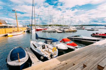 Oslo, Norway. The Wooden Sea Pier With Moored Boats And Yachts At Aker Brygge District. The Seascape Of Harbour And Quays In Summer Sunny Day Under Scenic Cloudy Sky.