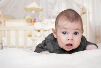 toothless baby lies on a stomach and with astonishment looks