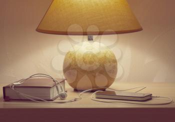 closed book with headphones and the phone on the table lighting table lamp