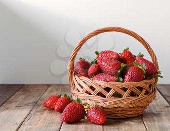 ripe strawberries in a wicker basket on a wooden table