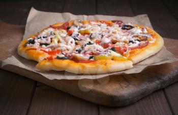 Pizza on cutting board and wooden table background
