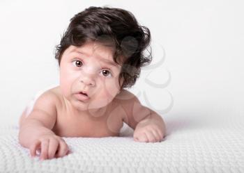 naked baby with dark shaggy hair on a white blanket