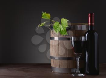 red wine bottle and wine glass on wooden barrel and the vine