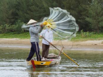 Fisherman is fishing with a large net in a river in Vietnam (Hoi An)