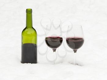 Bottle of red wine and wineglasses isolated in the cold snow