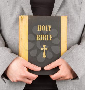 Woman in business suit is holding a holy bible, close-up
