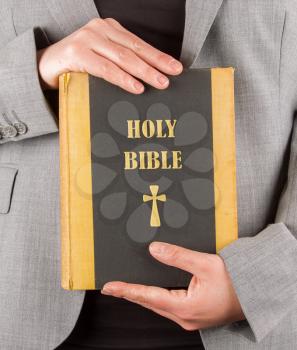 Woman in business suit is holding a holy bible, close-up