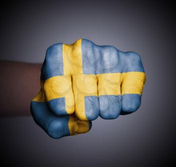 Front view of punching fist on gray background, flag of Sweden