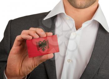 Businessman is holding a business card, flag of Albania