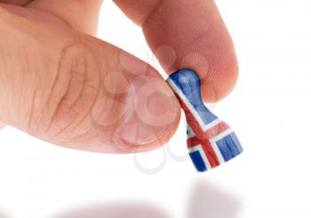 Hand holding wooden pawn with a flag painting, selective focus, Iceland
