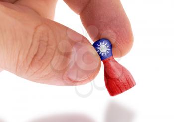 Hand holding wooden pawn with a flag painting, selective focus, Taiwan