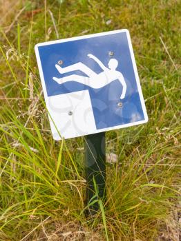 Blue falling hazard sign standing in the grass