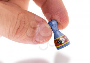 Hand holding wooden pawn with a flag painting, selective focus, Swaziland