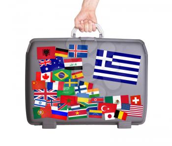 Used plastic suitcase with lots of small stickers, large sticker of Greece