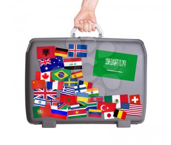 Used plastic suitcase with lots of small stickers, large sticker of Saudi Arabia