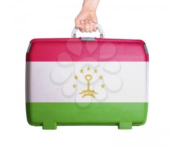 Used plastic suitcase with stains and scratches, printed with flag, Tajikistan